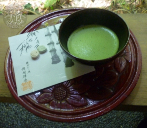 A bowl of foamy green tea, with sweets on the side